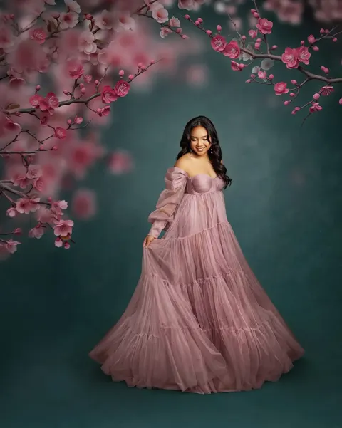 Retouched portrait of the same pose against a deep green background framed by pink cherry blossom branches